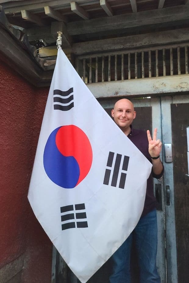 Joel standing behind a Korean flag