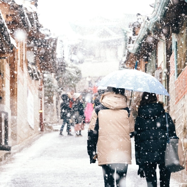 Couple walking through snow covered bukchon hanok village seoul