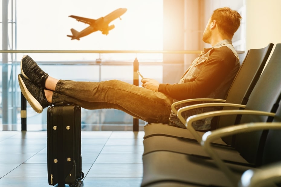 Man relaxing at an airport watching a plane depart