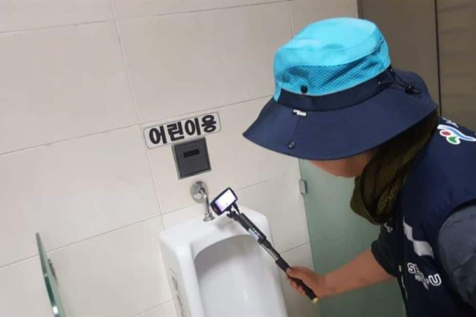 Person inspecting a Korean toilet for spy cameras