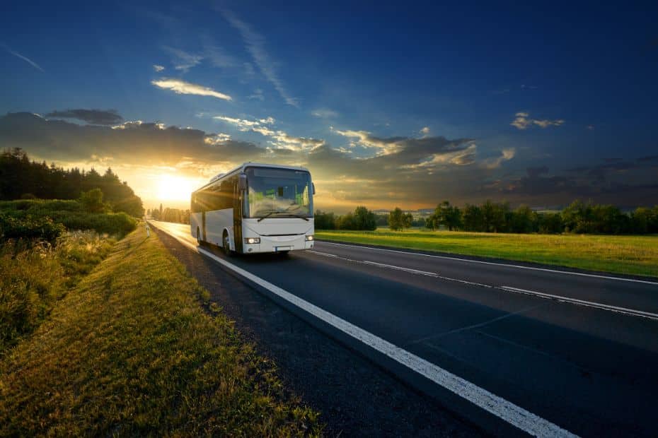 Tour bus on a road with sunset behind