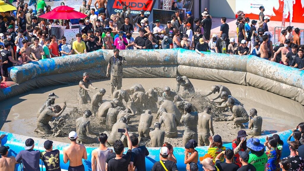Group of people having fun on the muddy ground in celebration of Boryeong Mud Festival