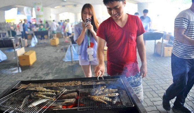 People participate in grilling sweetfish after their catch in Bonghwa Eun-uh (Sweetfish) Festival